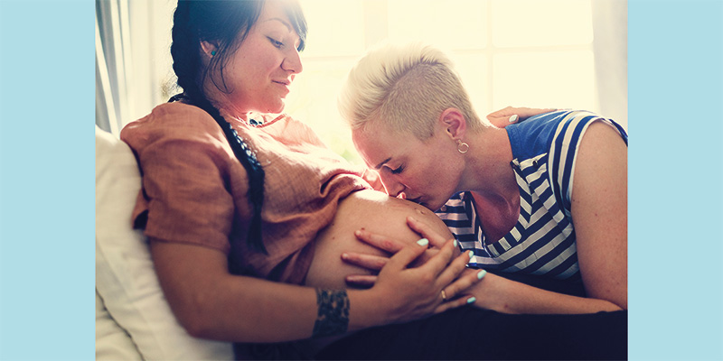 One woman kissing the pregnant belly of her wife or girlfiend.